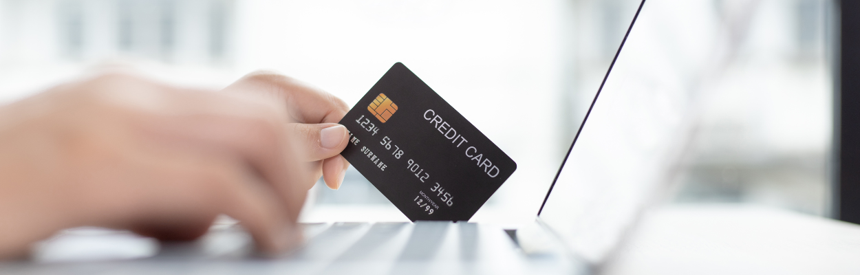 Karta kredytowa trzymana w dłoni i przykładana do komputera